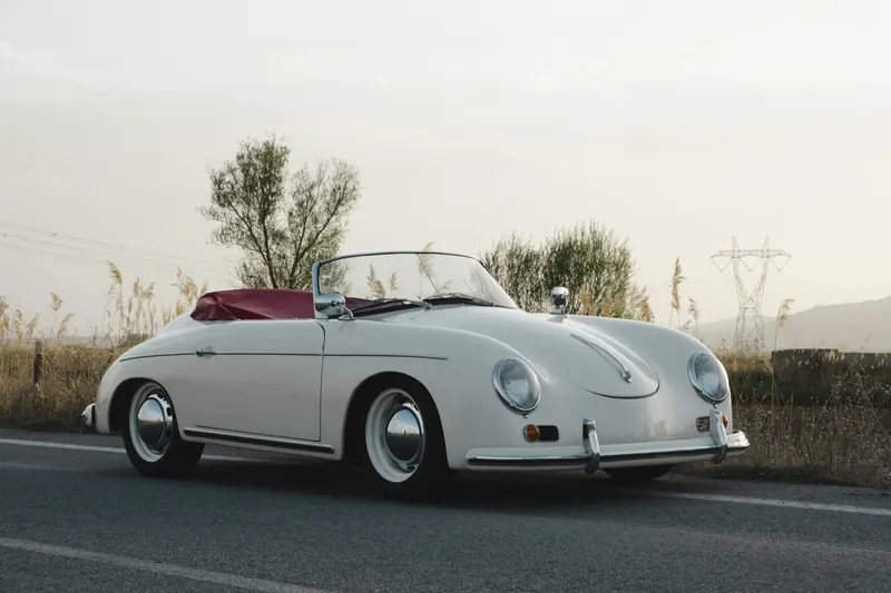 White Porsche 356 Speedster, front three-quarter view, on a country road.